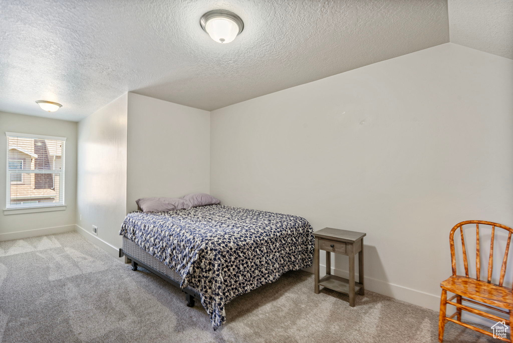 Carpeted bedroom with a textured ceiling and baseboards