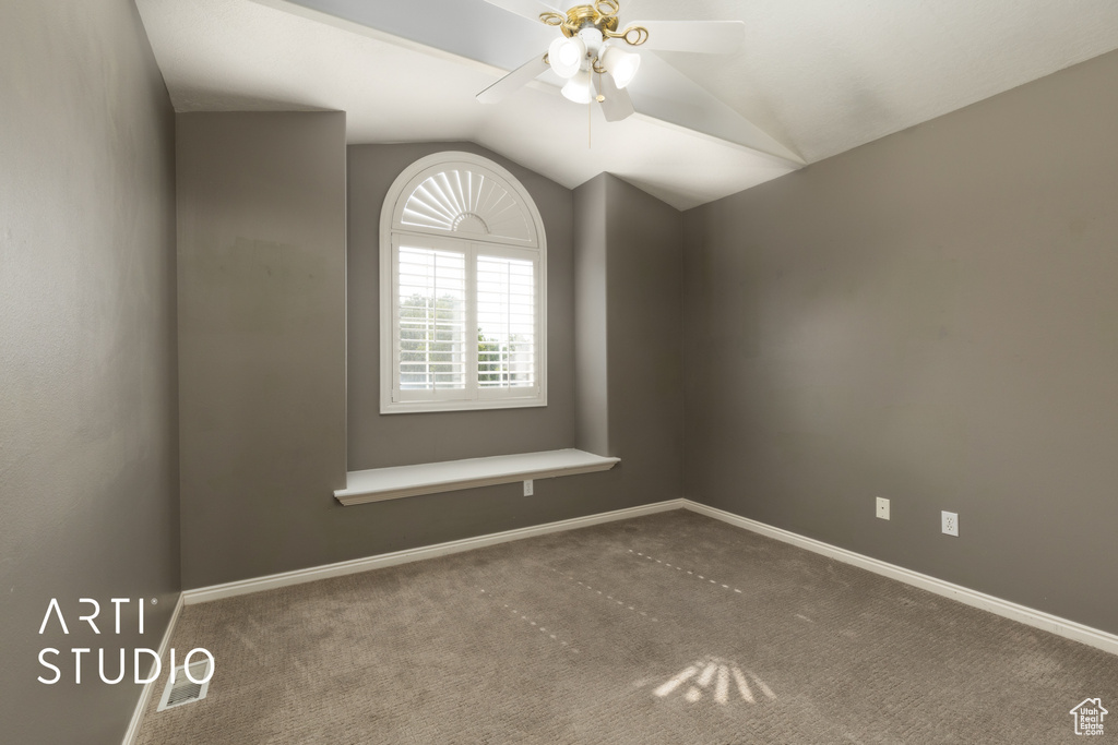 Spare room with ceiling fan, vaulted ceiling, and carpet flooring