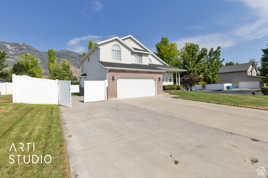 Traditional-style home with brick siding, concrete driveway, a garage, and a mountain view
