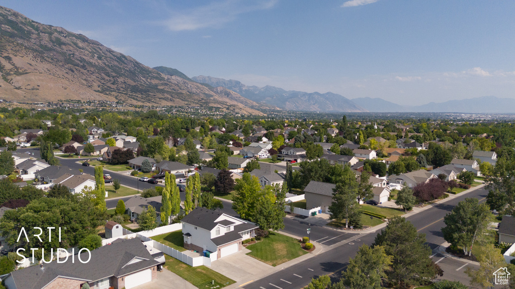 Aerial view of property and surrounding area featuring a mountainous background and nearby suburban area