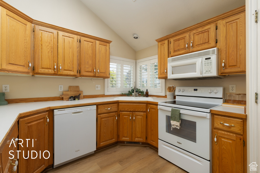 Kitchen with white appliances, vaulted ceiling, light wood-style flooring, light countertops, and brown cabinets