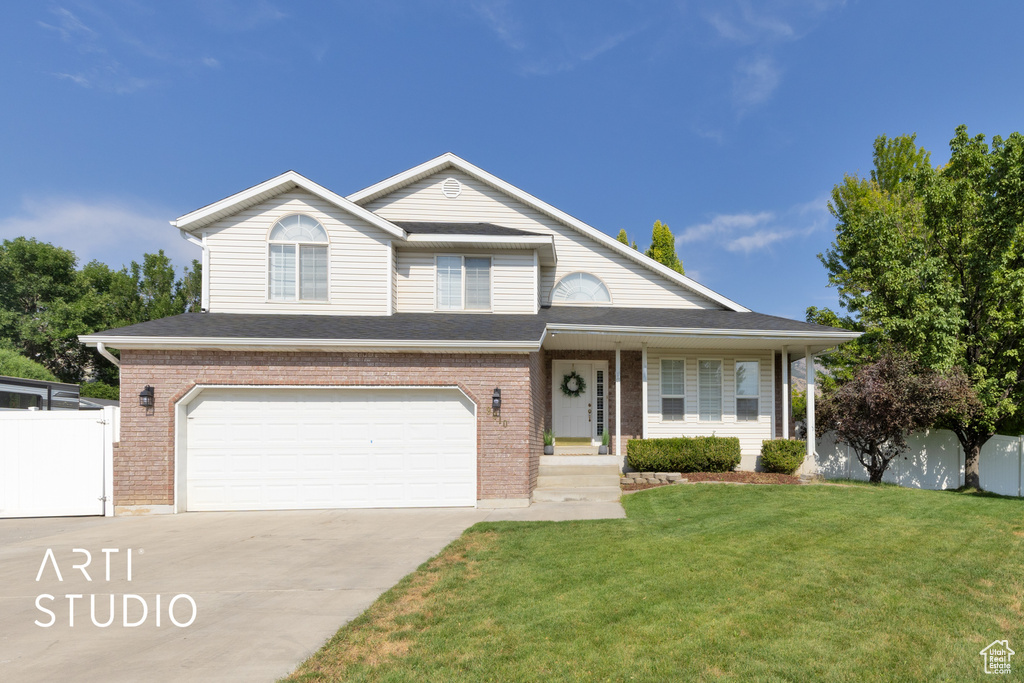 Traditional-style house with an attached garage, concrete driveway, brick siding, and covered porch