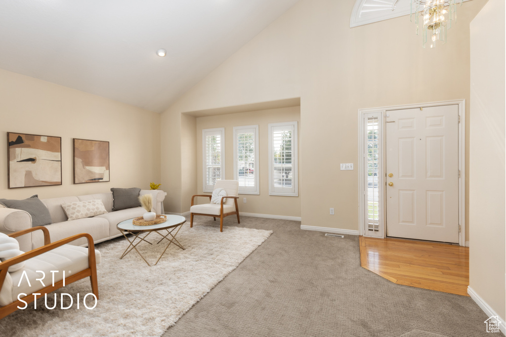 Carpeted living area with high vaulted ceiling and a chandelier