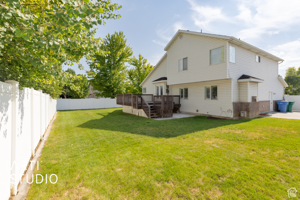 Back of house featuring a deck, a fenced backyard, a patio, stairs, and brick siding