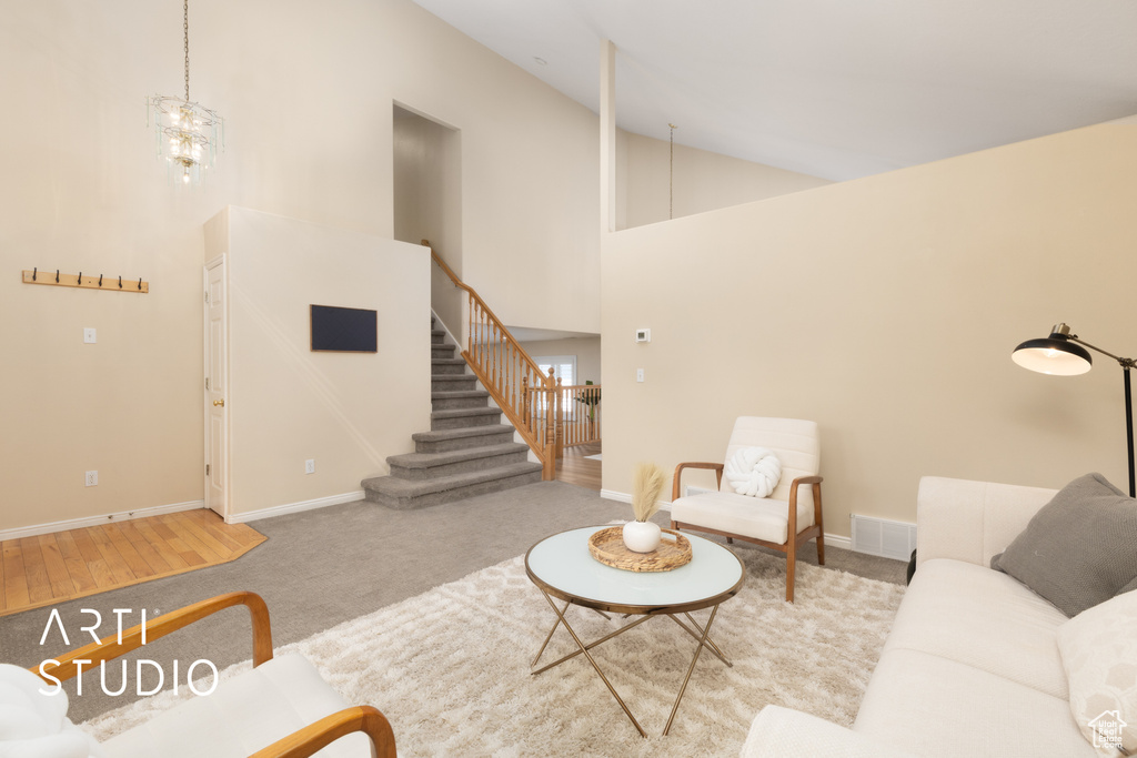 Living room with stairs, high vaulted ceiling, carpet, and a chandelier