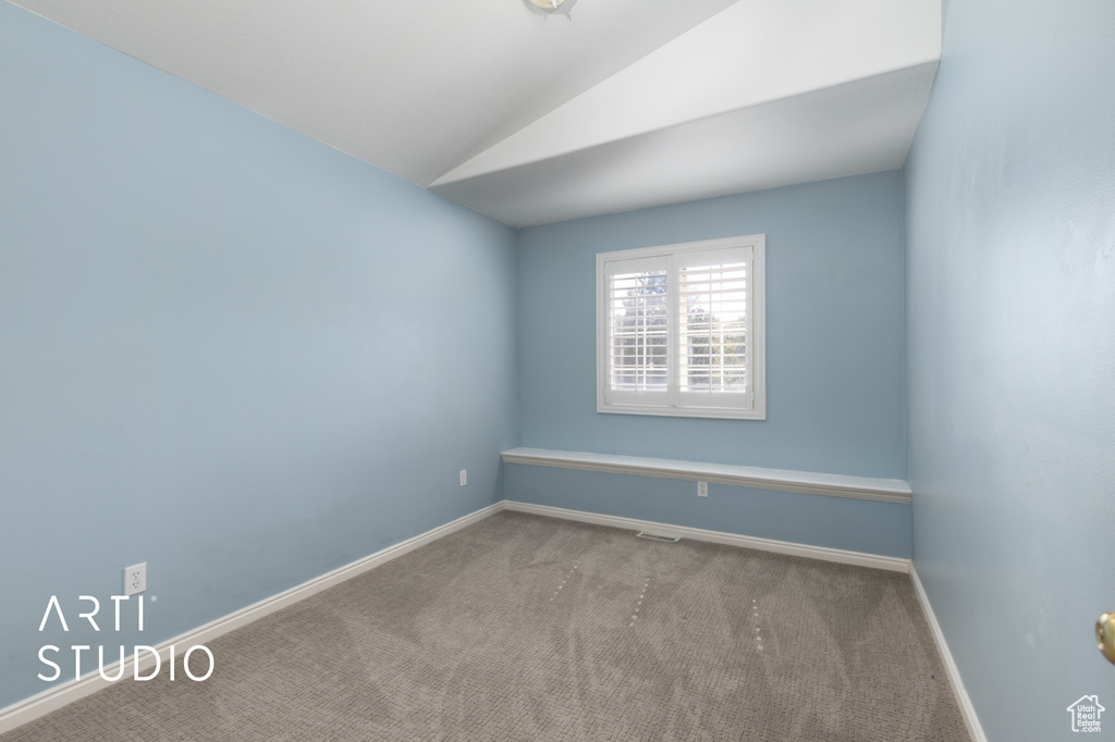 Spare room featuring carpet floors and lofted ceiling