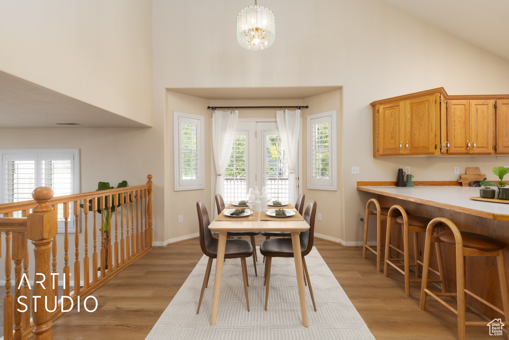 Dining space with high vaulted ceiling, light wood-style floors, and plenty of natural light