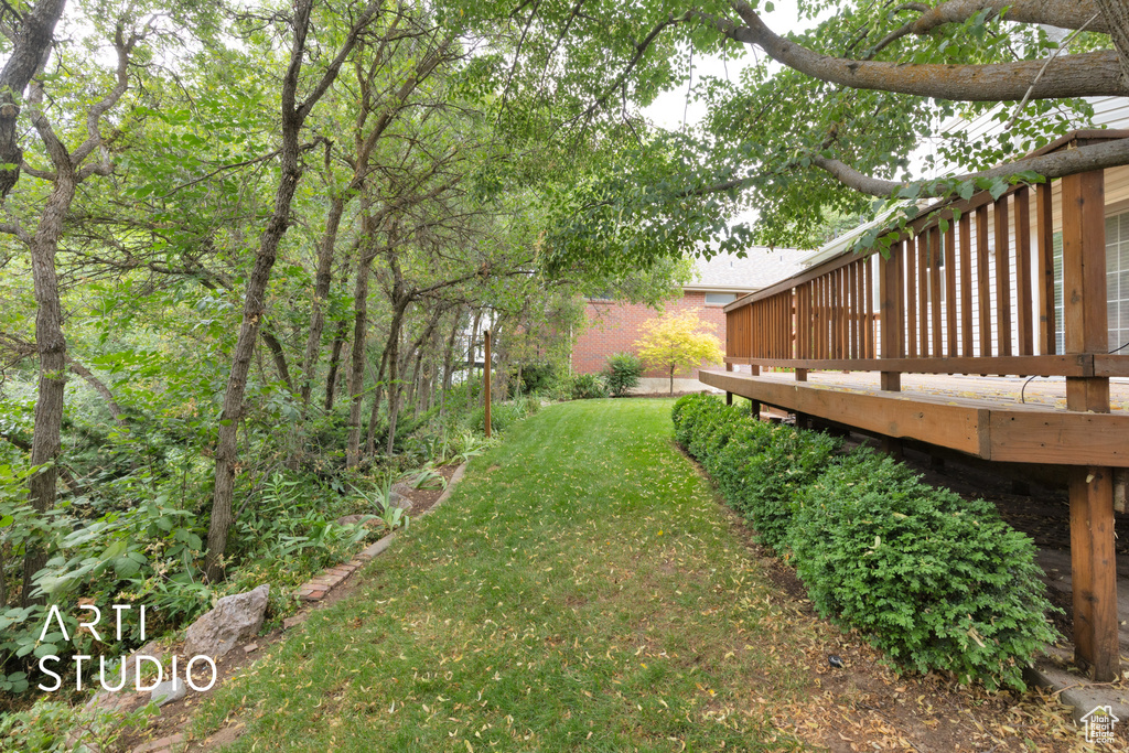 View of green lawn featuring a wooden deck