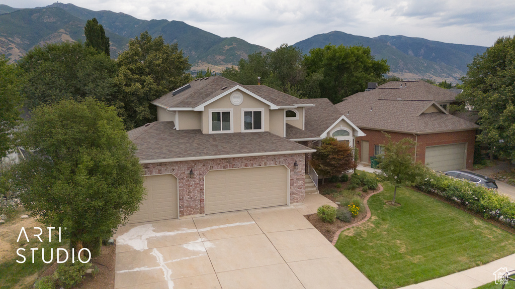 Traditional-style house with roof with shingles, a mountain view, a front yard, brick siding, and driveway