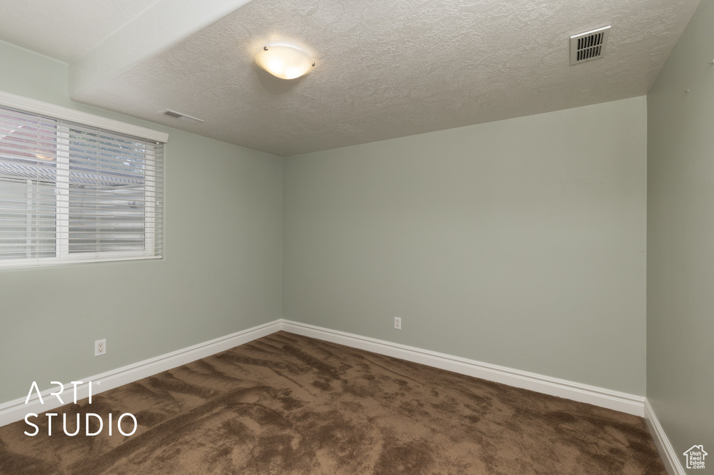Carpeted spare room with baseboards and a textured ceiling