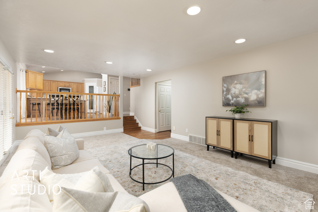 Living area with stairway, light colored carpet, and recessed lighting