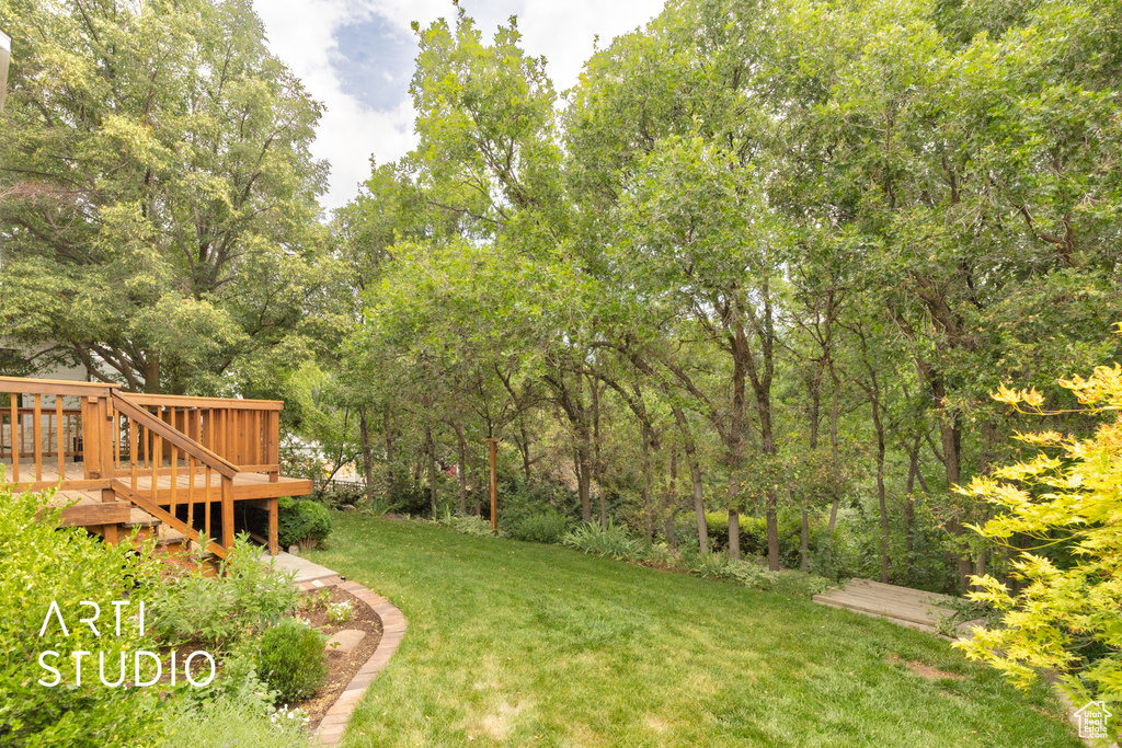 View of grassy yard featuring a wooden deck