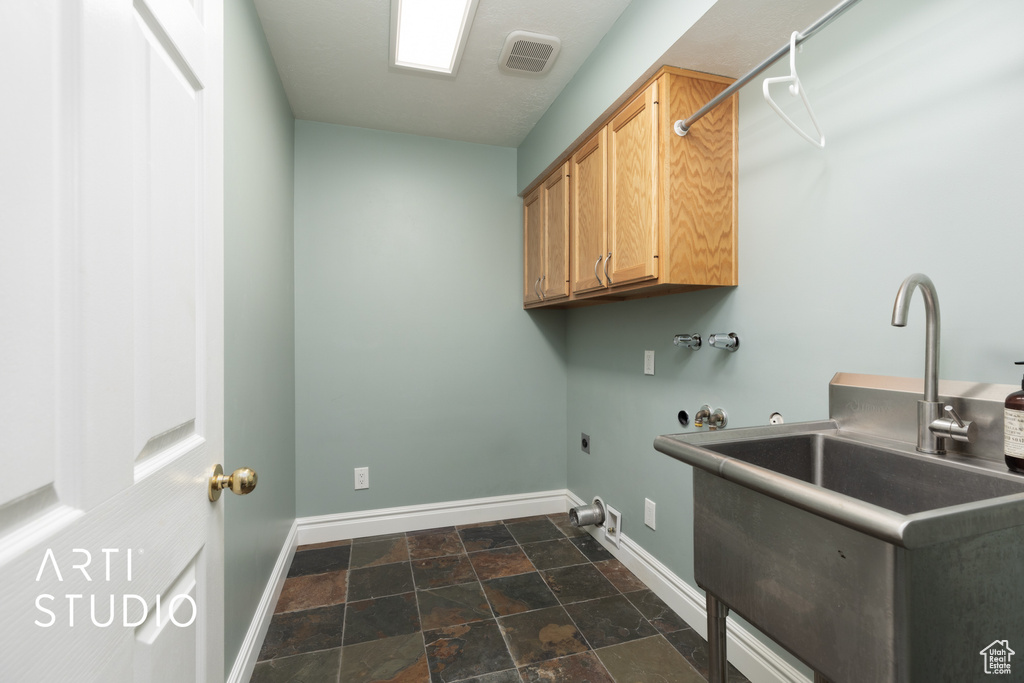 Washroom with cabinet space, dark stone finish flooring, hookup for an electric dryer, and washer hookup