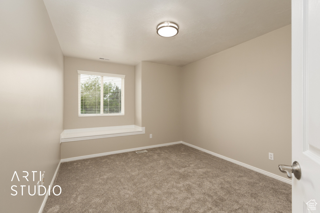 Spare room featuring carpet flooring and baseboards