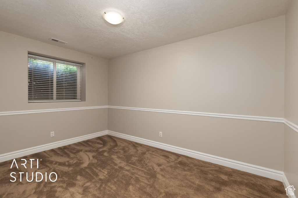 Carpeted spare room featuring baseboards and a textured ceiling