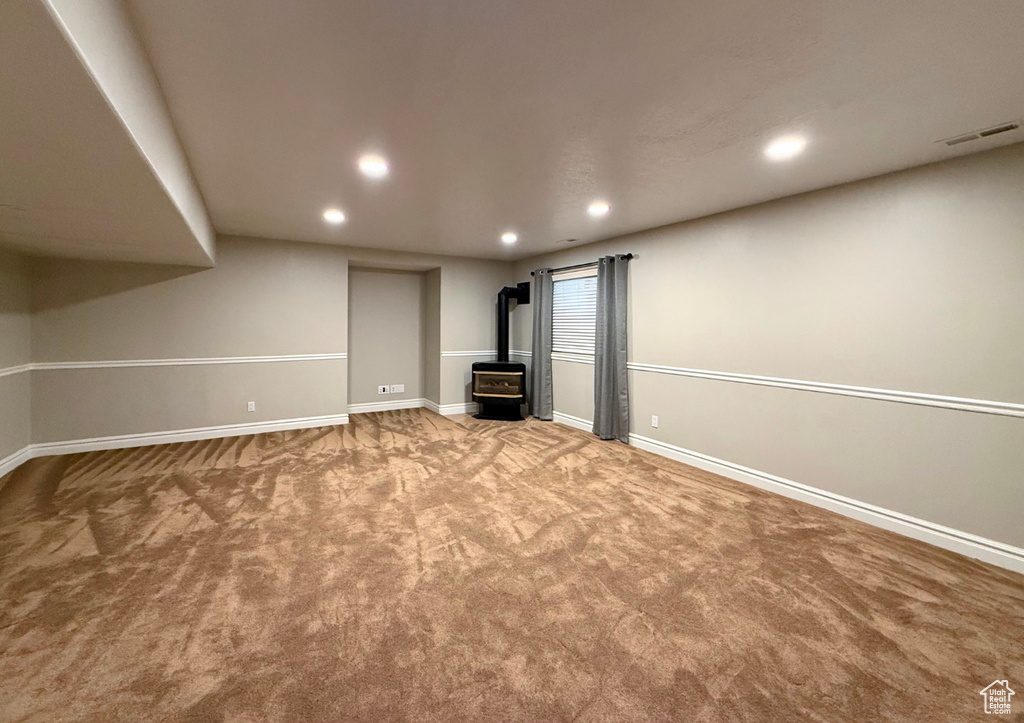 Basement featuring a wood stove, carpet flooring, and recessed lighting