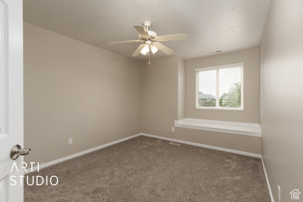 Carpeted empty room featuring baseboards and ceiling fan