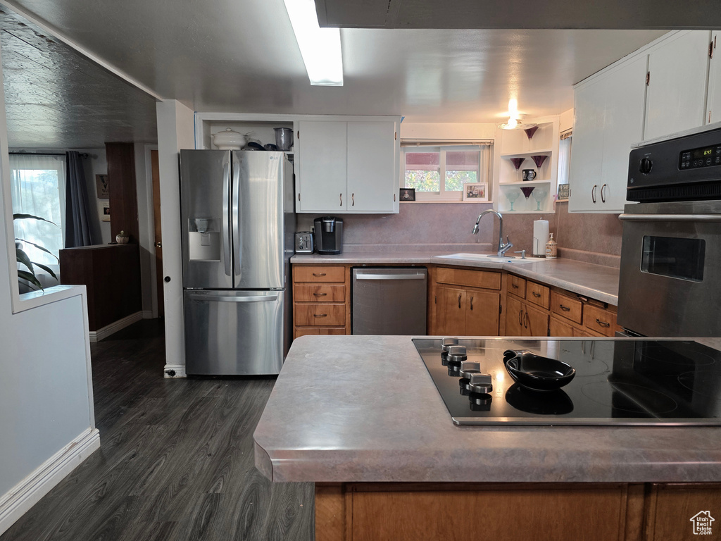 Kitchen with stainless steel appliances, dark wood finished floors, white cabinetry, and open shelves