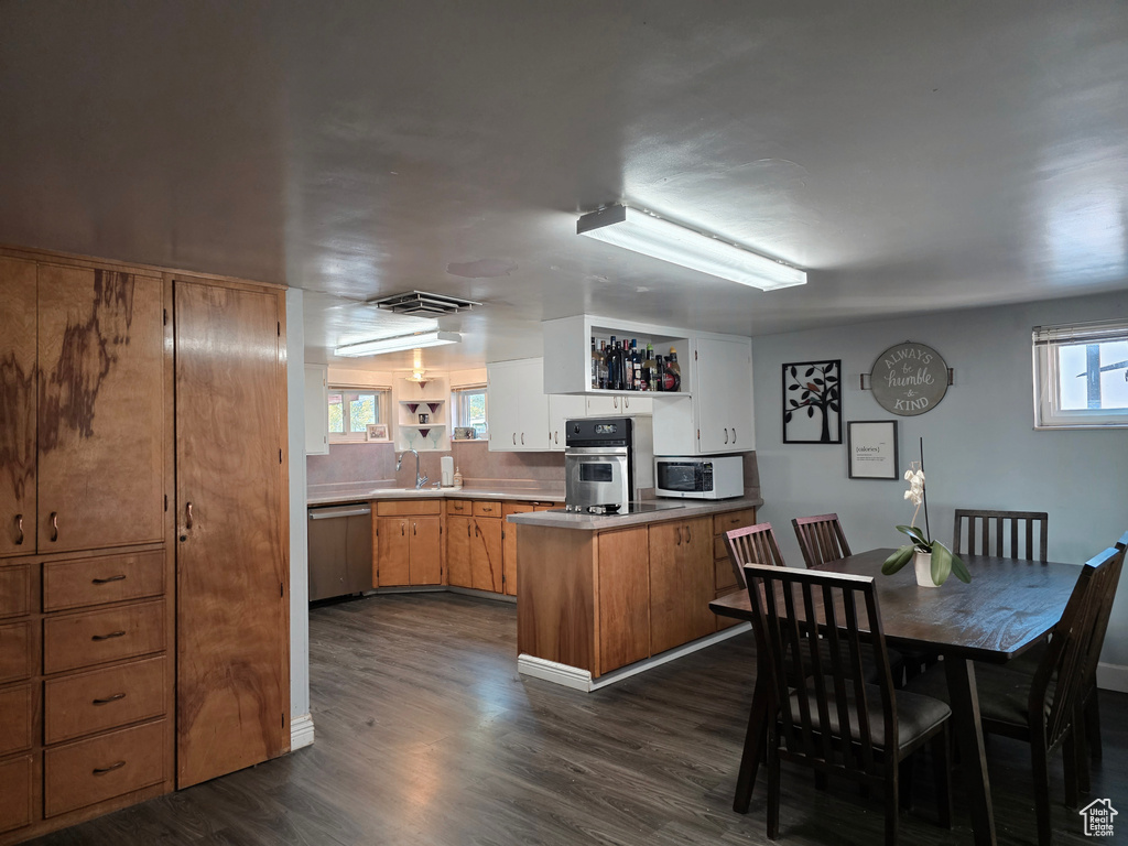 Kitchen featuring open shelves, appliances with stainless steel finishes, a peninsula, and dark wood-type flooring