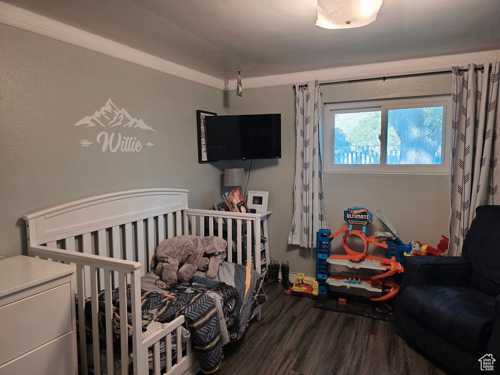 Bedroom featuring wood finished floors and crown molding