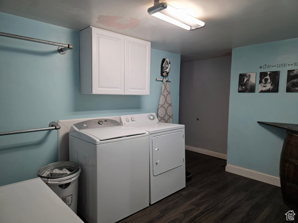 Washroom featuring cabinet space, washing machine and clothes dryer, and dark wood-style flooring