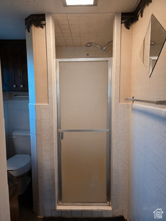 Full bath with a shower stall and tile walls