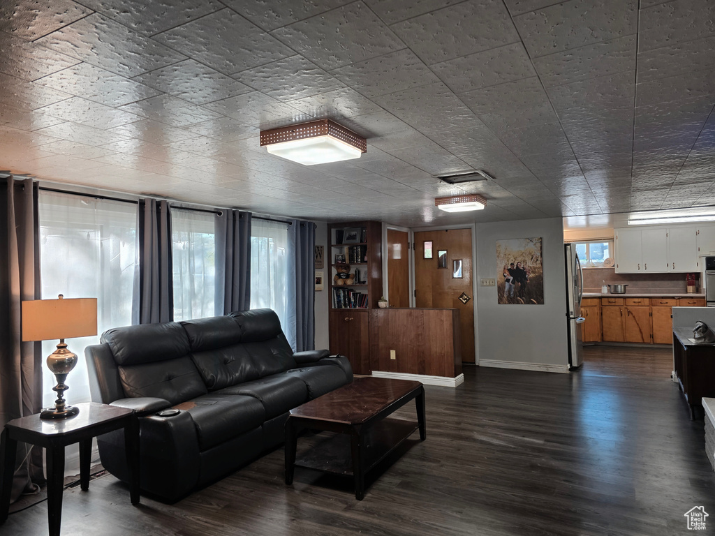 Living area featuring dark wood-style floors and baseboards