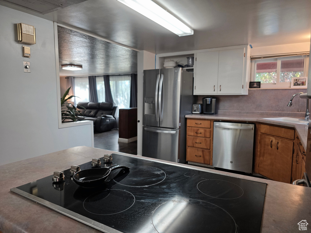 Kitchen featuring appliances with stainless steel finishes, white cabinetry, healthy amount of natural light, and brown cabinetry