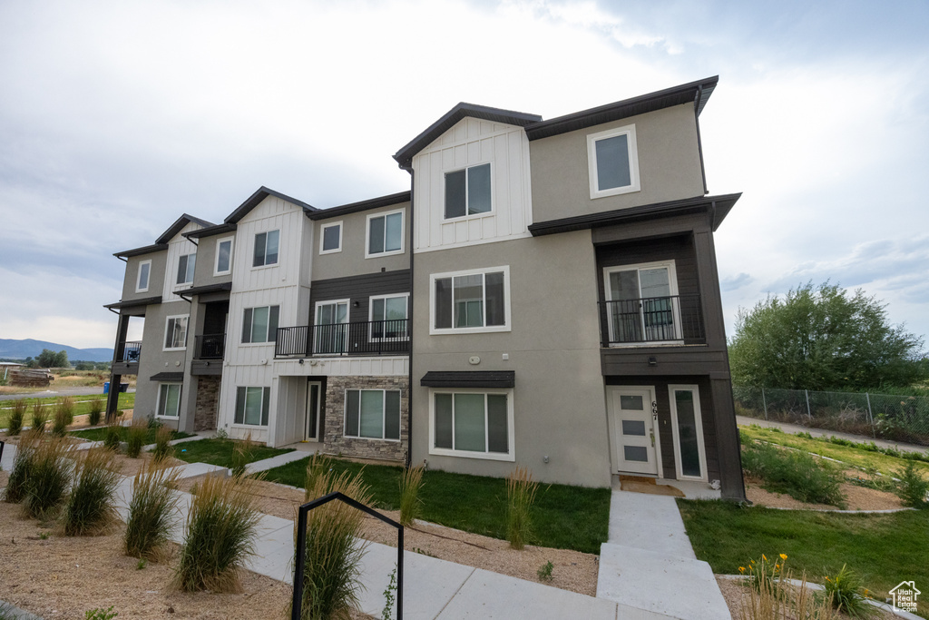 View of front of property featuring board and batten siding, stucco siding, and stone siding