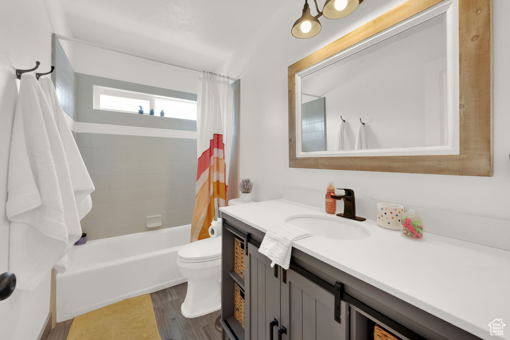 Bathroom with vanity, shower / bath combo, and wood finished floors