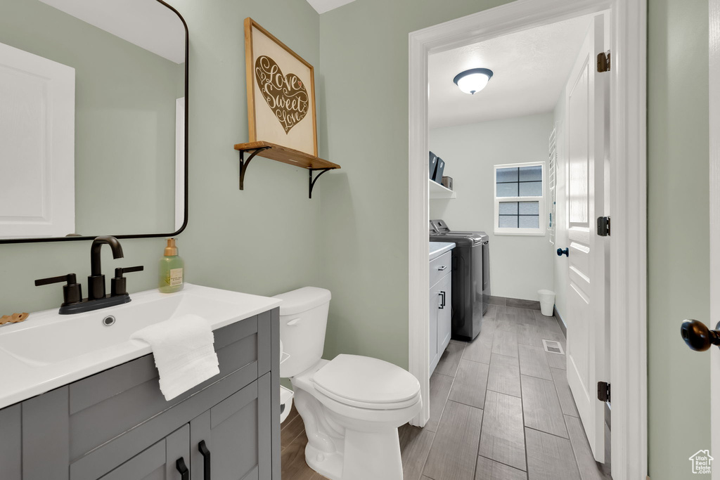 Bathroom featuring washer and dryer, vanity, and wood tiled floors