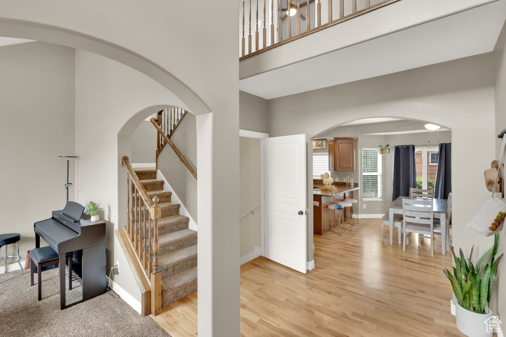 Staircase with wood finished floors, arched walkways, and a towering ceiling