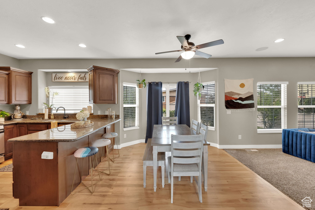 Kitchen with a ceiling fan, a kitchen bar, recessed lighting, light wood-type flooring, and a peninsula