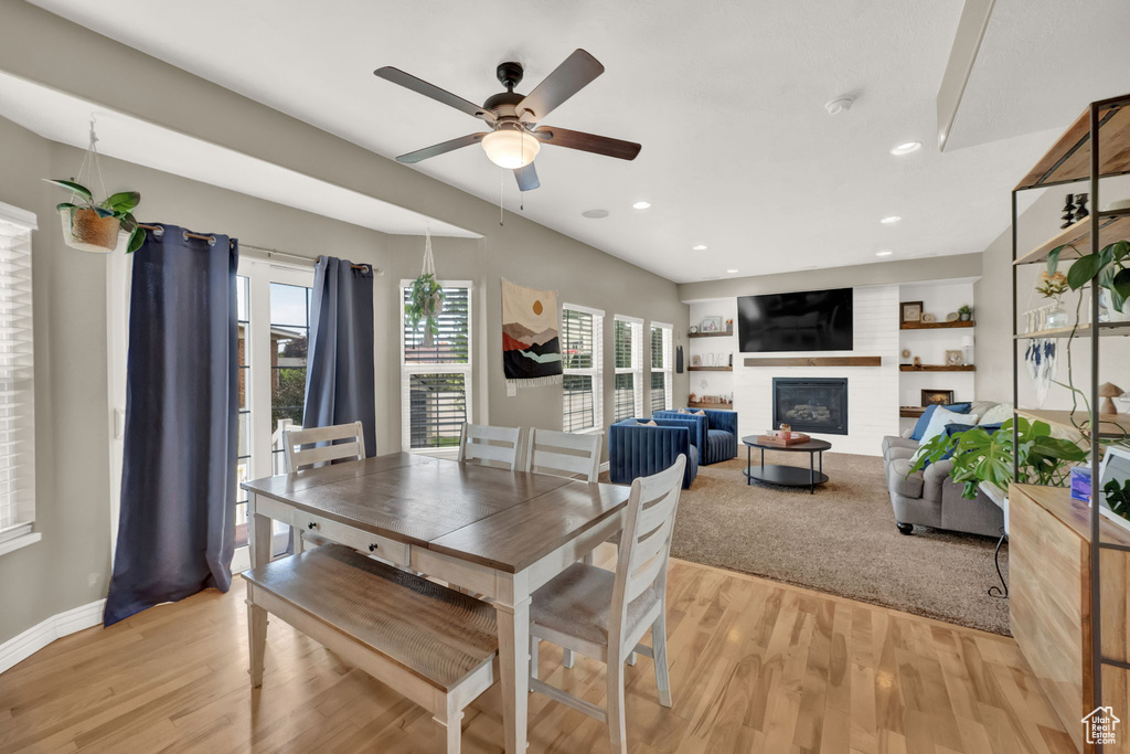 Dining area featuring a glass covered fireplace, ceiling fan, light wood finished floors, plenty of natural light, and recessed lighting