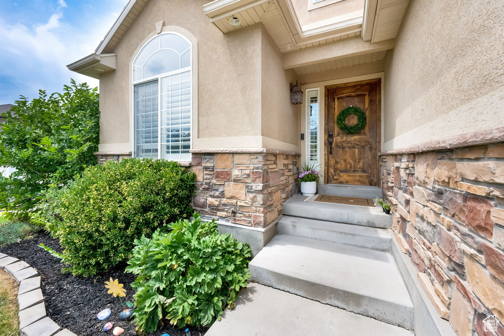 View of exterior entry with stone siding and stucco siding