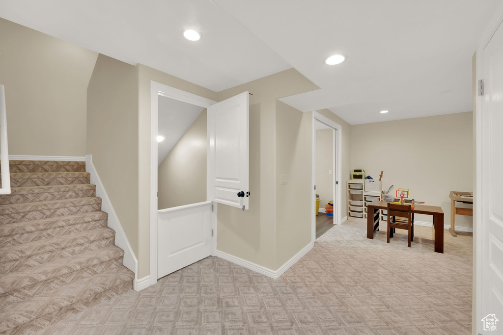 Below grade area featuring light colored carpet, recessed lighting, stairway, and an office area