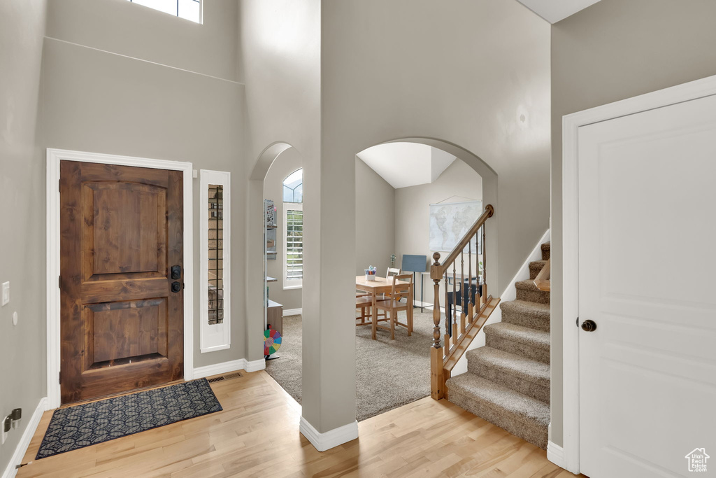 Foyer entrance featuring arched walkways, plenty of natural light, a high ceiling, wood finished floors, and stairway