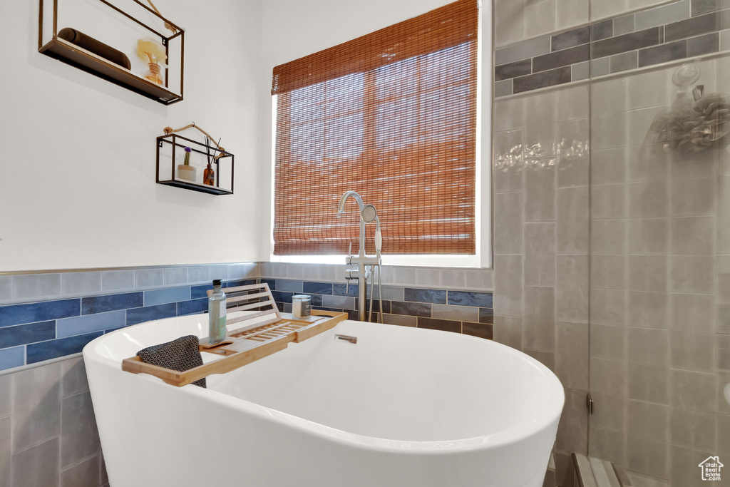 Full bathroom with tile walls, a freestanding bath, and a wainscoted wall