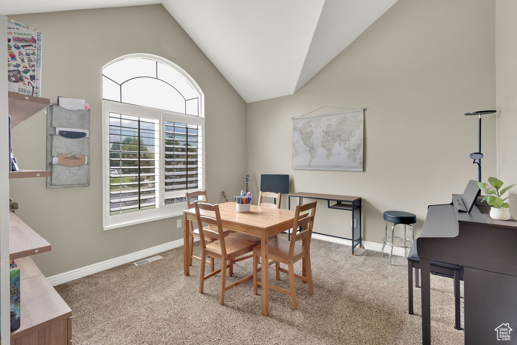 Carpeted dining area with lofted ceiling and a desk