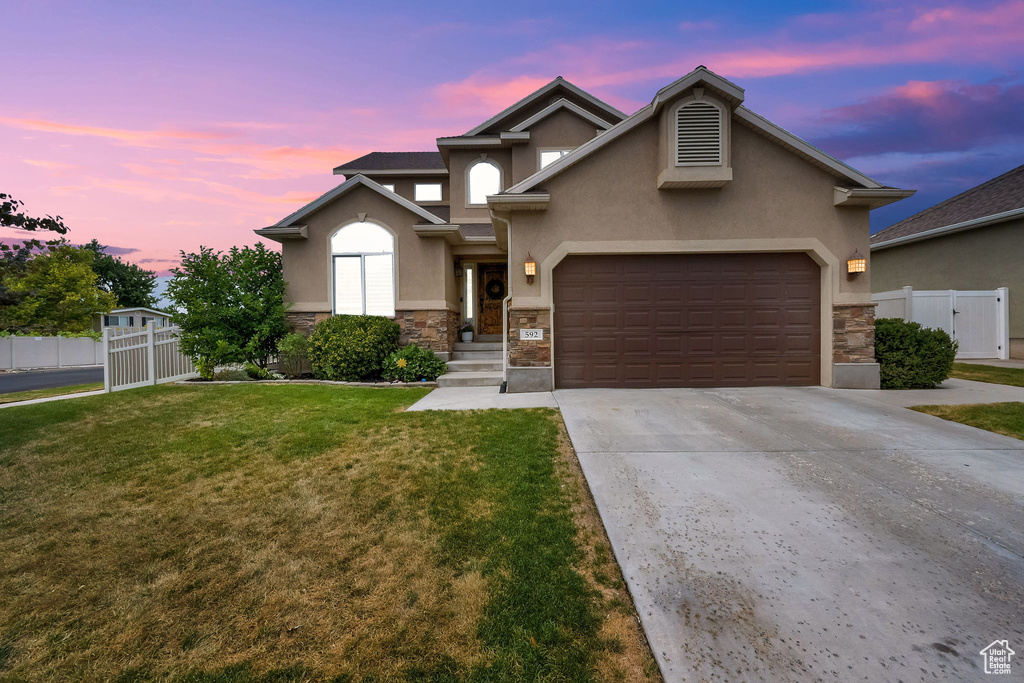 View of front of property with stucco siding, stone siding, a garage, and concrete driveway