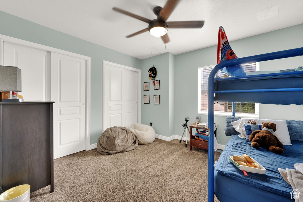 Carpeted bedroom with ceiling fan and two closets