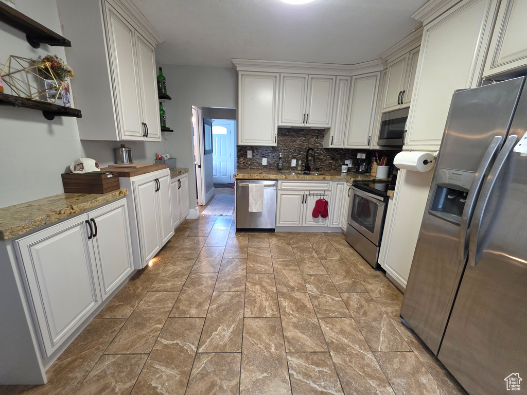 Kitchen with open shelves, stainless steel appliances, tasteful backsplash, and white cabinets