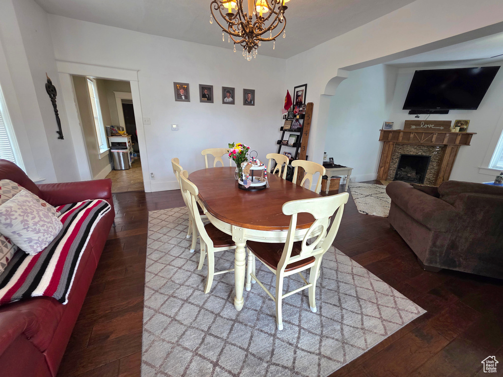 Dining space with a chandelier, wood finished floors, a high end fireplace, and arched walkways
