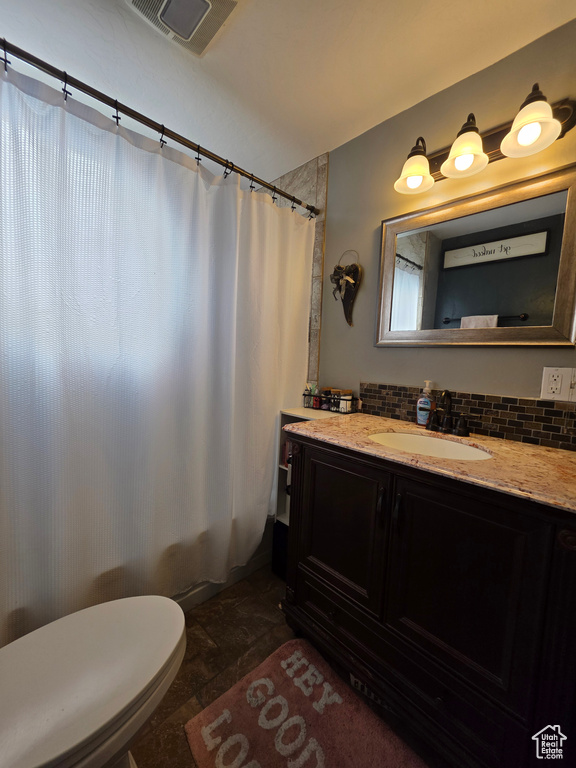 Bathroom featuring vanity, shower / bath combo, and tasteful backsplash