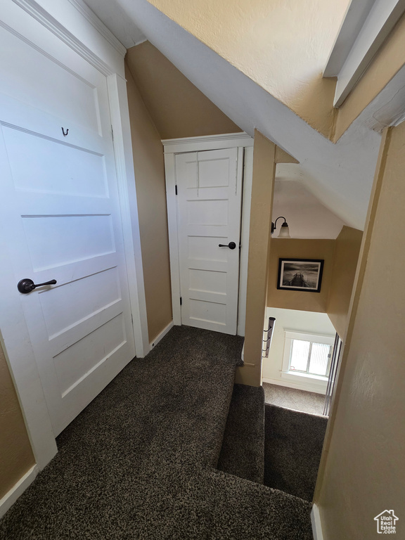Corridor with dark carpet and vaulted ceiling