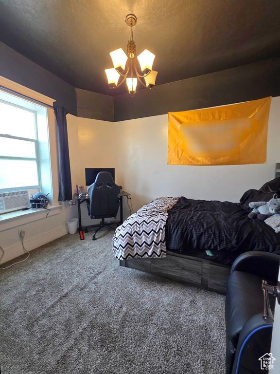 Carpeted bedroom with a chandelier, a desk, and a textured ceiling