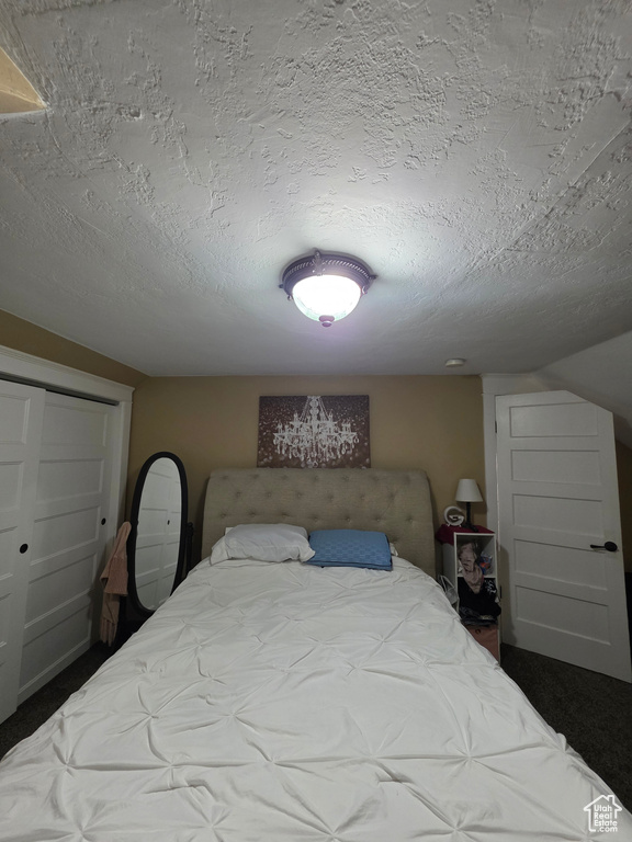 Bedroom with a textured ceiling and dark colored carpet