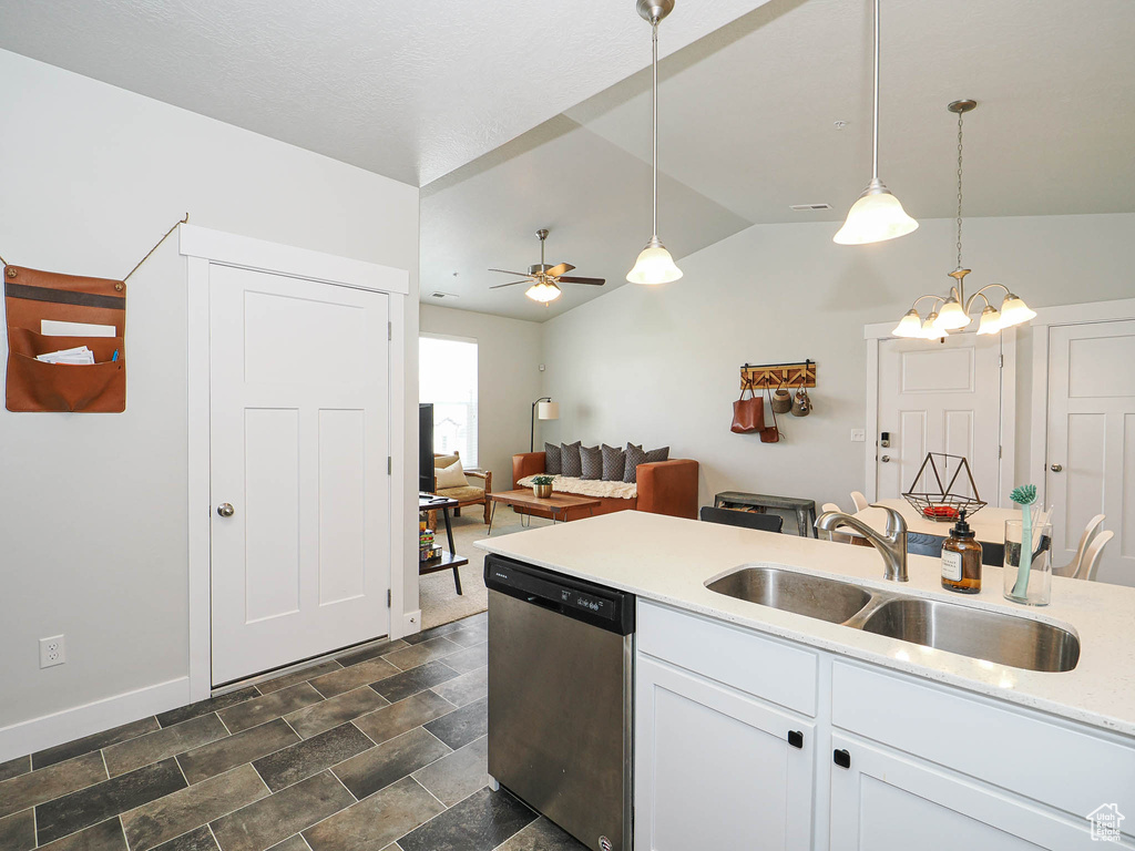 Kitchen featuring dishwasher, lofted ceiling, light countertops, decorative light fixtures, and white cabinets