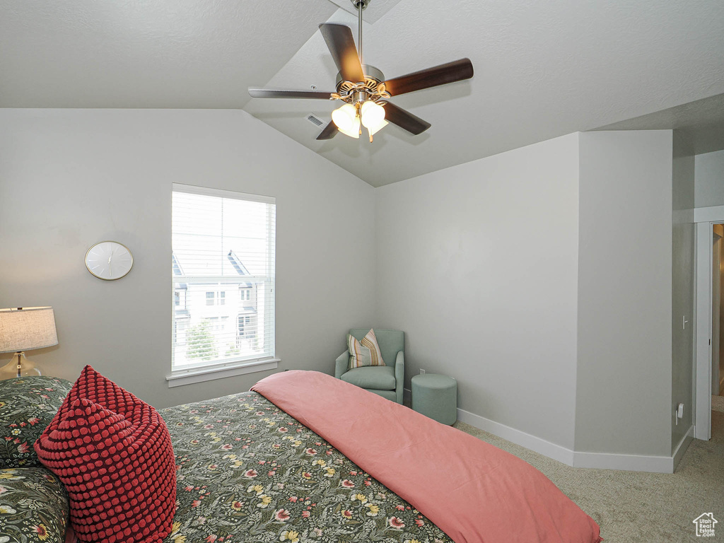 Carpeted bedroom with vaulted ceiling and a ceiling fan
