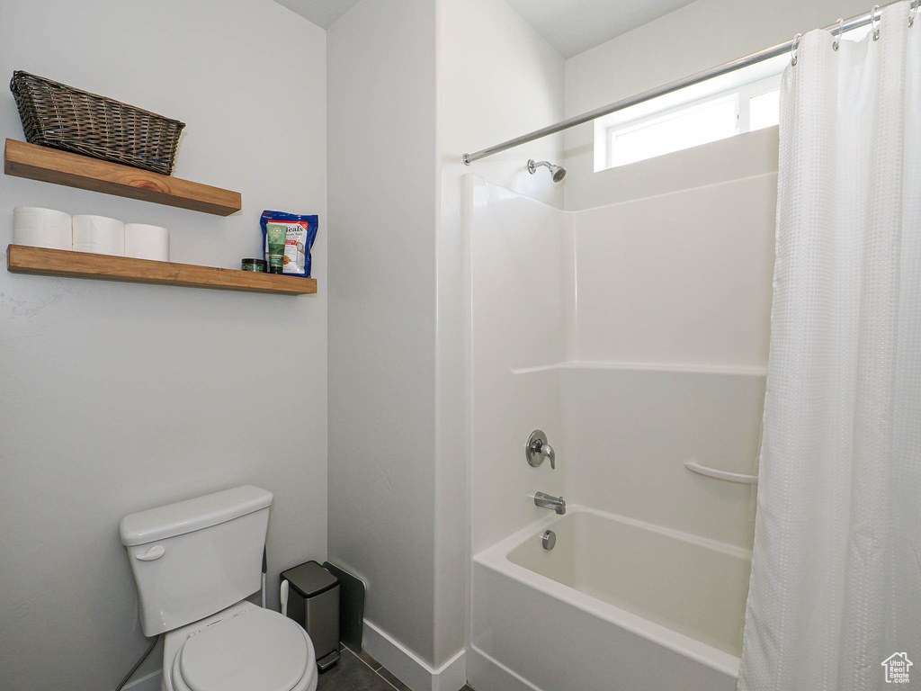 Bathroom featuring toilet and shower / bath combo with shower curtain